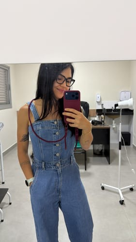 Avaliadora tira uma selfie no espelho usando a funcional Cordinha Nora bordô pendurada no pescoço.
