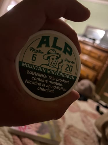 Customer holding the round, white can of Mountain Wintergreen Nicotine Pouches.