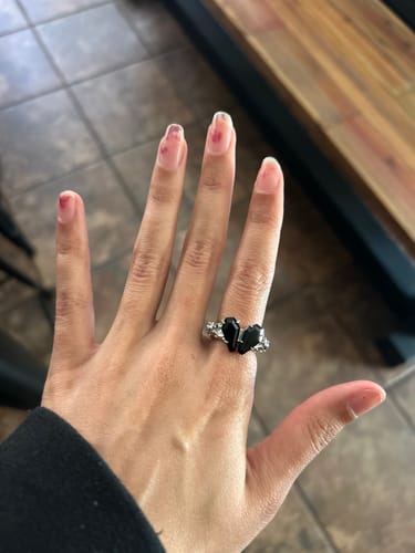 Reviewer's hand wearing the Promise Ring, showing the two black coffin-shaped stones that form a heart.