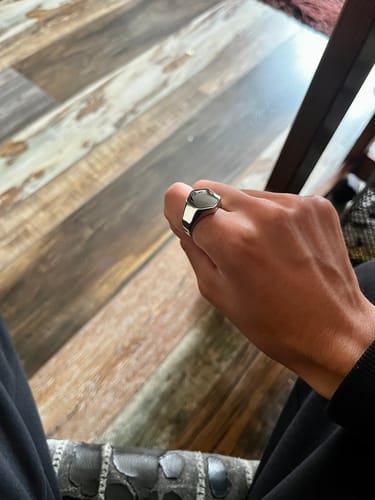 Un cliente usando el Anillo Classic Onyx plateado en su mano sobre un fondo de madera.