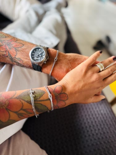 Customers' wrists side by side, each wearing a silver Forever Knot Bracelet.