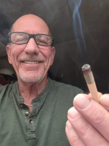 Customer smiling while holding a lit Royal Cherry Pre-Roll.