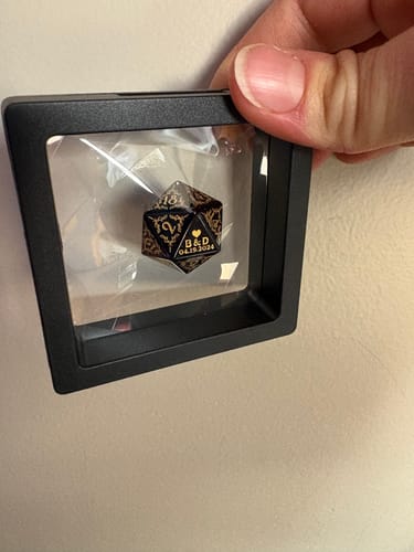 Reviewer holding a display case with a custom engraved black and gold die showing the number 18.