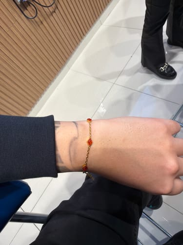 Cliente luciendo la Pulsera Red Gem Oro en su muñeca con gemas rojas.