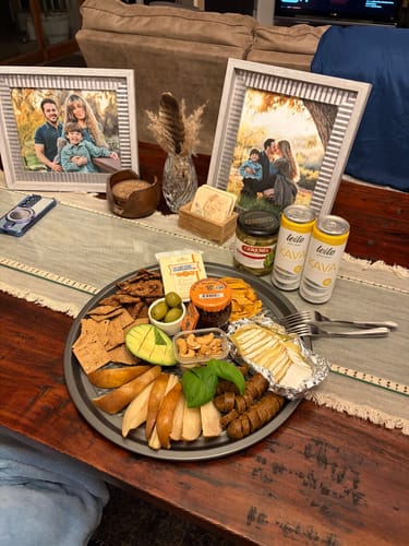 Customer's two Kava Tonic cans next to a large charcuterie board on a wooden table for a date night.