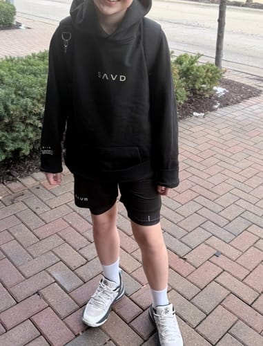 A customer's child wearing the black Youth Oversized Hoodie, showing its comfortable oversized fit.