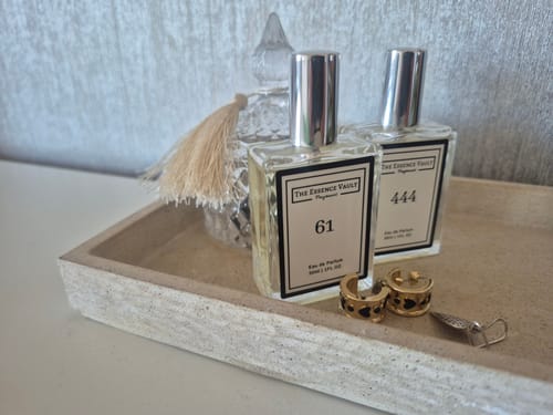 Reviewer's 'Inspired by Lost Cherry - 444' perfume bottle sitting on a decorative tray next to another perfume bottle.