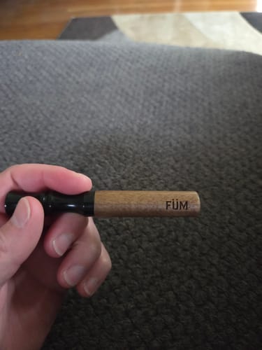 A reviewer holds their FÜM device from the Journey Pack, showing its wooden barrel and black mouthpiece.