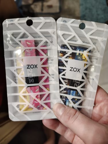 Customer holding two Zox bracelets in their packaging, including the Happy Birthday Bracelet.