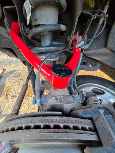 Close-up of the reviewer's installed red tubular control arm from the suspension lift kit on their truck.