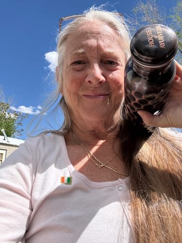 Reviewer smiling outdoors while holding their Antique Black Diamond-Cut Copper Water Bottle.