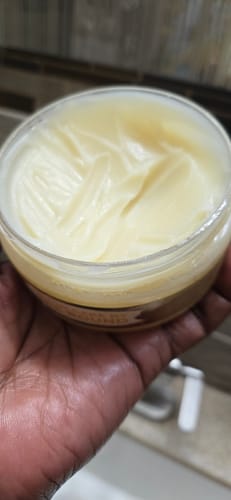 Customer holding an open jar of Body Glaze, showing its thick, creamy texture.