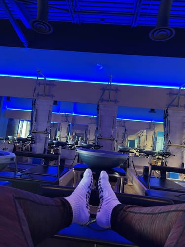 Reviewer wearing white Sunkissed socks with grippy soles in a pilates studio.