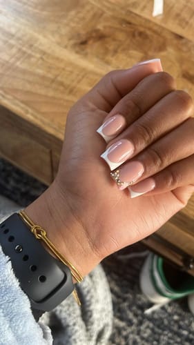 Close-up of a reviewer's wrist showing a delicate gold knot bracelet.