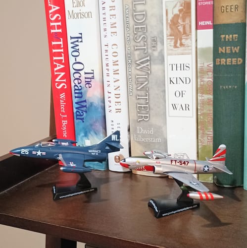 Customer's silver F80 Shooting Star model on a shelf with another model airplane and history books in the background.