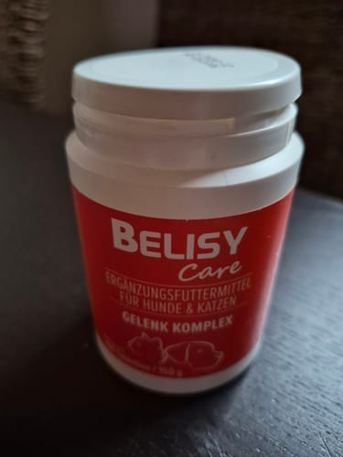 Rezensent zeigt die Dose des Gelenk Komplex auf einem dunklen Tisch.