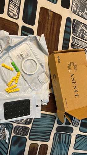 Customer shows the new Magsafe Clear Case for iPhone 13 unboxed on a table next to its packaging and accessories.