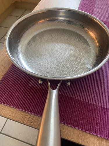 Kundenfoto der gehämmerten Titanpfanne mit ihrer texturierten, glänzenden Innenfläche auf einem Tisch.