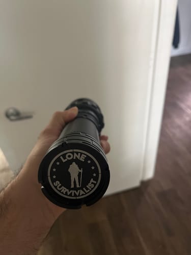 Customer holding the black Shire Light, showing the 'Lone Survivalist' logo on the end cap.