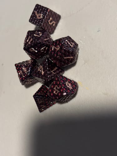 Customer's dark, textured Blood Red Dragon's Egg Metal Dice Set piled on a white surface.