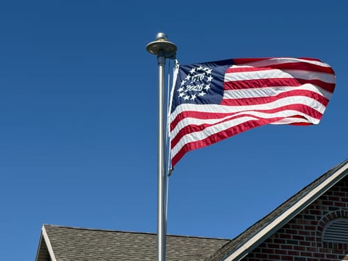 Customer's 1776 to 2026 Betsy Ross Flag waving from a flagpole against a clear blue sky.