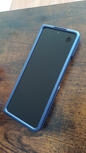 Customer's Samsung Galaxy Z Fold 5 in a blue case, folded shut on a wooden table.