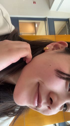 A close-up of a reviewer wearing the small Celestial Gold Hoop Earring in their ear.