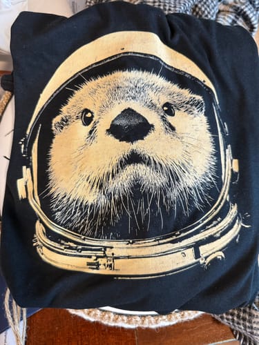 Customer's black Otterspace shirt with a graphic of an otter wearing an astronaut helmet.