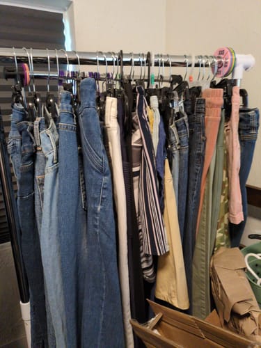 Customer's assortment of Carhartt pants and jeans from the wholesale box hanging on a clothing rack.