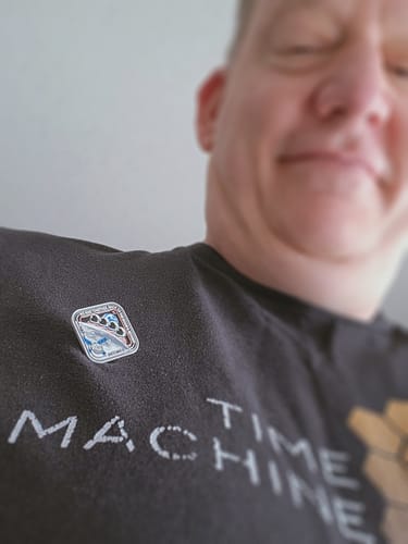 Reviewer showing the square Artemis II - Collectors Pin attached to their dark t-shirt.