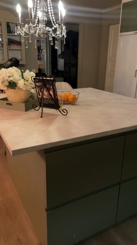 Kundes kjøkkenøy sett fra siden med en benkeplate i Emmy beige kontaktplast med en fin steinstruktur.