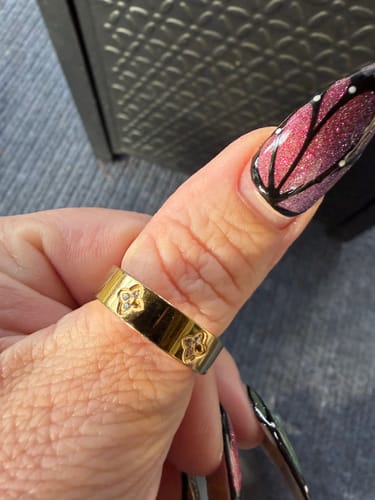 Customer's hand wearing the gold Eloise Ring on their thumb, showing the clover pattern.