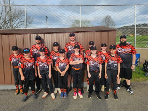 Customer's youth baseball team posing together in their custom orange and black tiger-stripe jerseys.