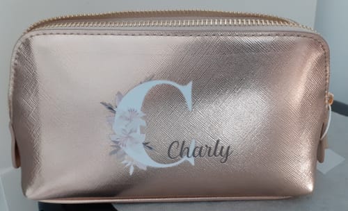 Kundenbild einer roségoldenen Kosmetiktasche, personalisiert mit einem floralen Buchstaben 'C' und dem Namen 'Charly'.