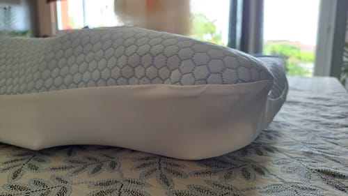 Gros plan d'un client sur le coussin d'alignement cervical Cellsius, montrant sa housse blanche à motifs.