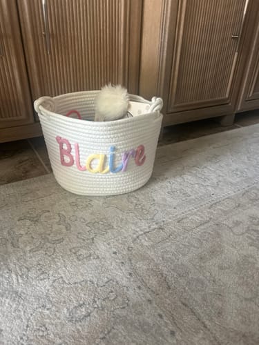 Customer's white knitted basket personalized with the name 'Blaire' in multicolor yarn letters.