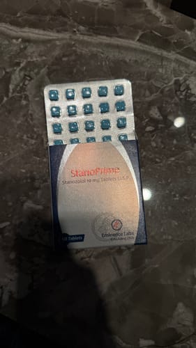 Cliente mostrando su caja de Stanoprime con el blíster de tabletas azules.
