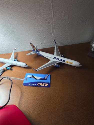Customer's GEMINI200 ATLAS 767-300ER model airplane displayed on a wooden desk next to another model.