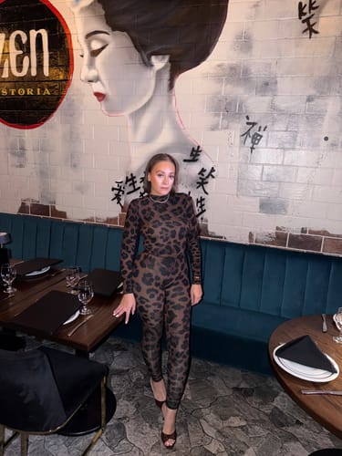 Reviewer showing a full view of the Naked Print Bodysuit and matching leggings in a restaurant.