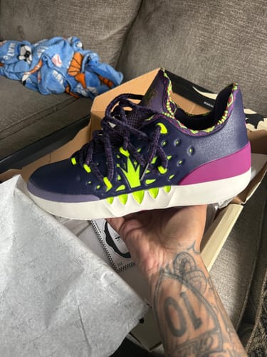 Customer holding a dark purple Joker 2 'Joker' shoe with lime green and magenta accents over its open box.