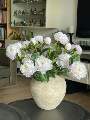 Klant toont de prachtige Zijden Pioenrozen in een beige vaas op een salontafel.
