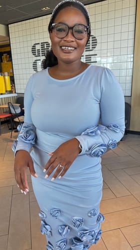 Close-up of a reviewer wearing the elegant floral pleat midi dress, showing the 3D appliqués on the sleeves.