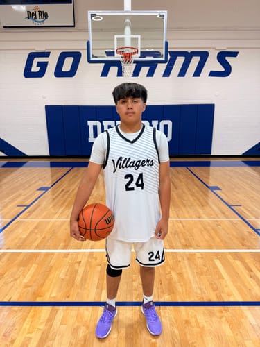 A customer wearing the white and black custom basketball uniform on an indoor court, holding a basketball.