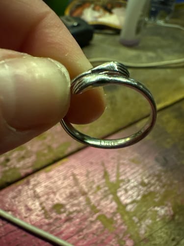 Close-up of a reviewer holding the silver Hug From Heaven Ring, showing the detailed design of two hands hugging.
