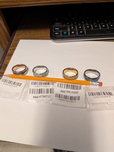 Reviewer's Vanguard ring with a silver band and blue inlay, displayed with three other rings on a desk.