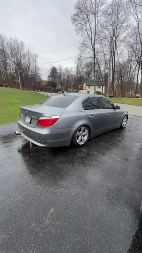 Customer's gray BMW sedan on a wet driveway, showing the wheels installed with the aftermarket lug bolts.