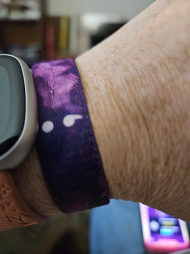 Close-up of a reviewer's wrist wearing the purple Continue Bracelet with a white semicolon symbol, next to a smartwatch.