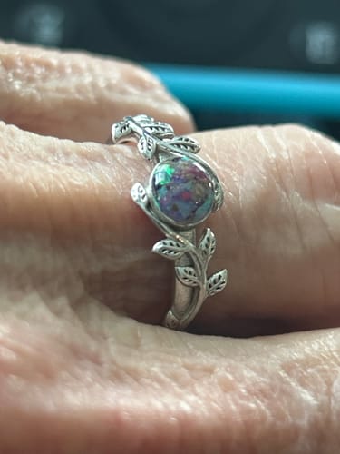 Close-up of a customer wearing the Leaf Opal Cremation Ring, showing the intricate silver leaf band and multi-colored opal.