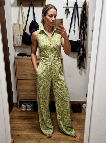 Reviewer taking a mirror selfie in the loose, green leopard-print pants.