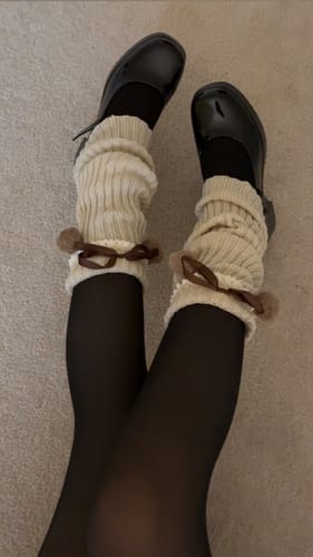 Reviewer wearing the Tessa Milk Tea Pom-Pom Knit Leg Warmers scrunched over black tights and shoes.
